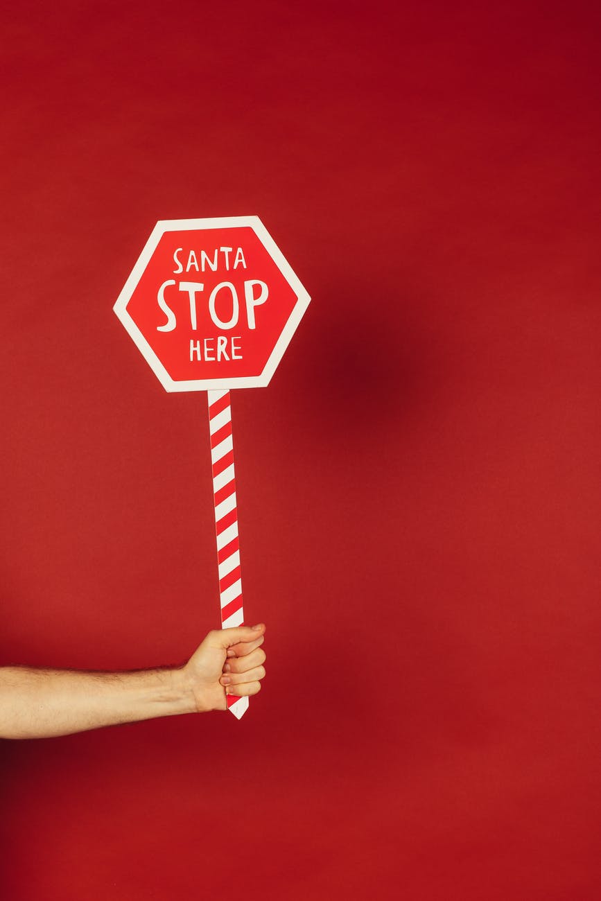 person holding red and white santa stop here sign