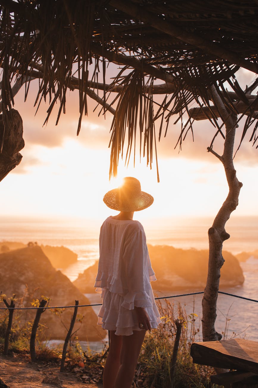 unrecognizable woman enjoying sunset over sea