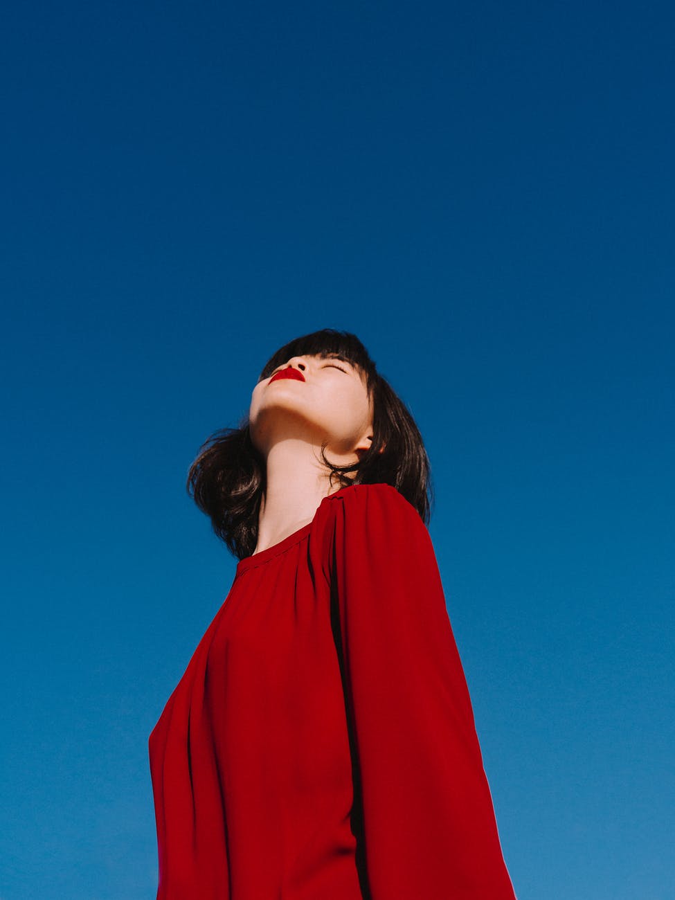 stylish asian woman with bright red lips enjoying sunny weather